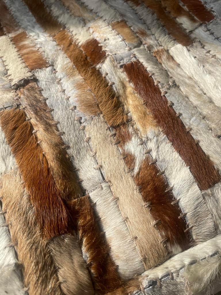 Unieke poef van koeienhuid - Patchwork design, Huis en Inrichting, Banken | Voetenbanken en Poefen, Verzenden, Rond, Leer, Zo goed als nieuw
